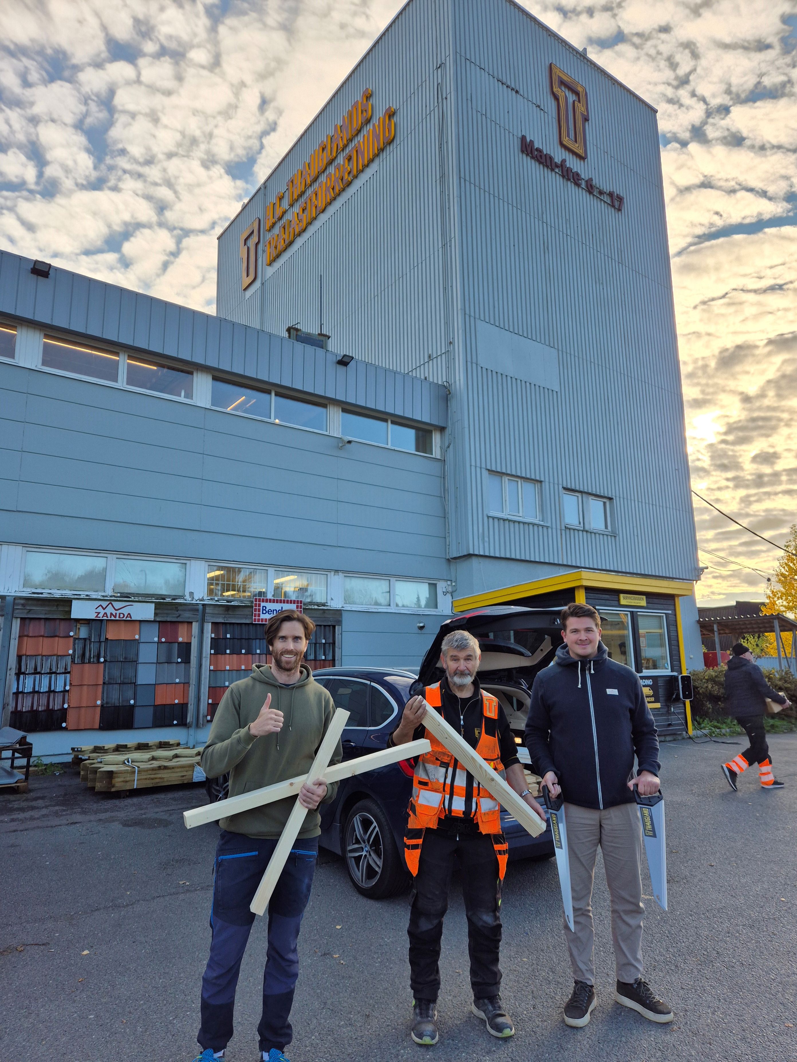 en gruppe mennesker som holder en stor fisk foran en bygning