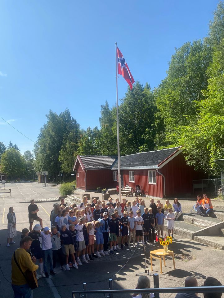 en gruppe mennesker som poserer for et bilde foran en flaggstang
