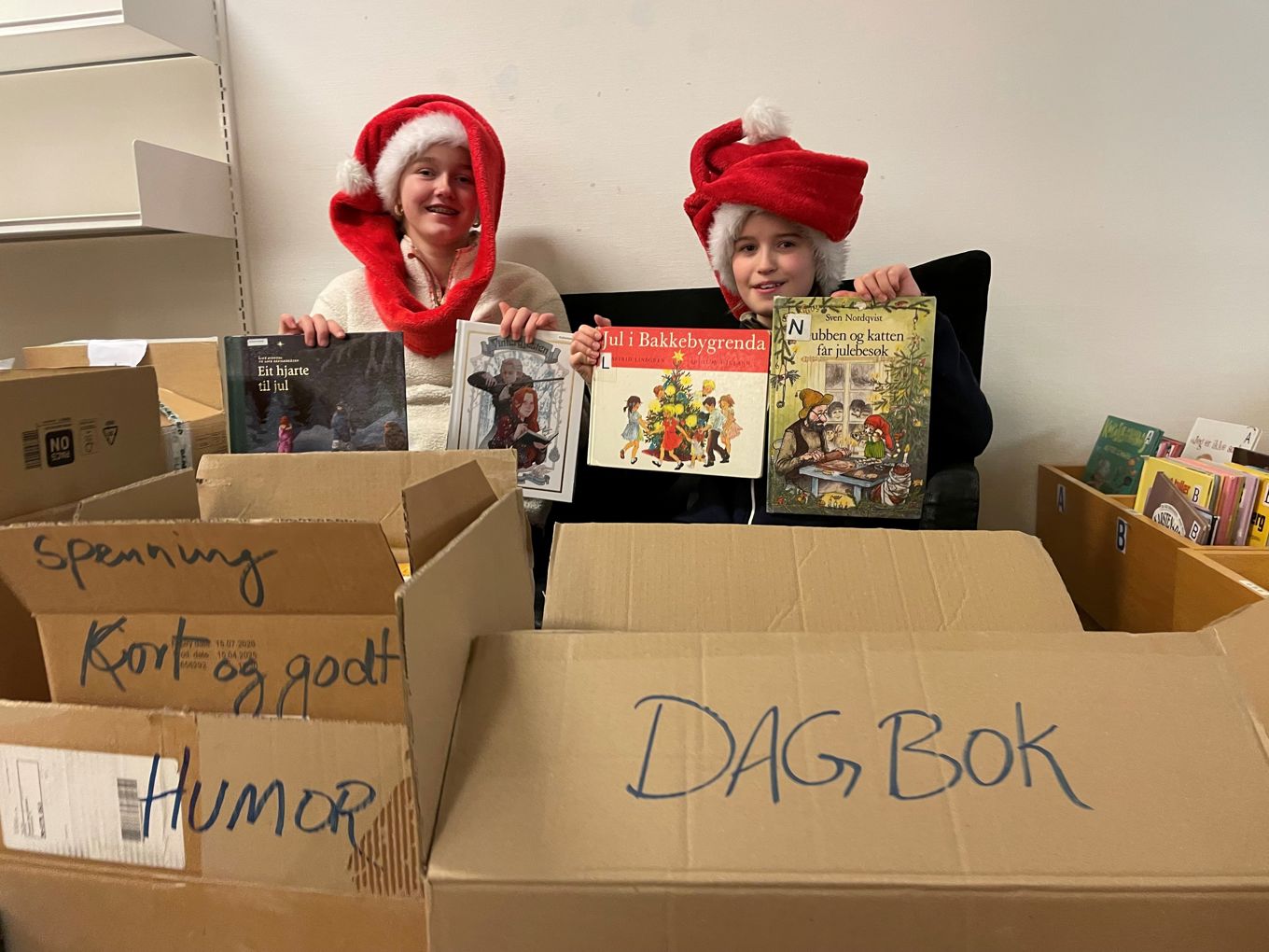 Et par barn i nisseluer som holder esker Et par barn i nisseluer som holder esker