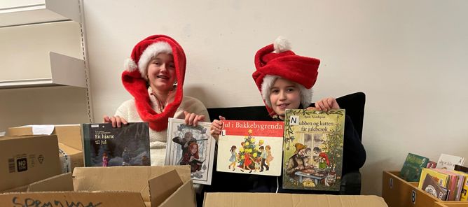 Et par barn i nisseluer som holder esker Et par barn i nisseluer som holder esker