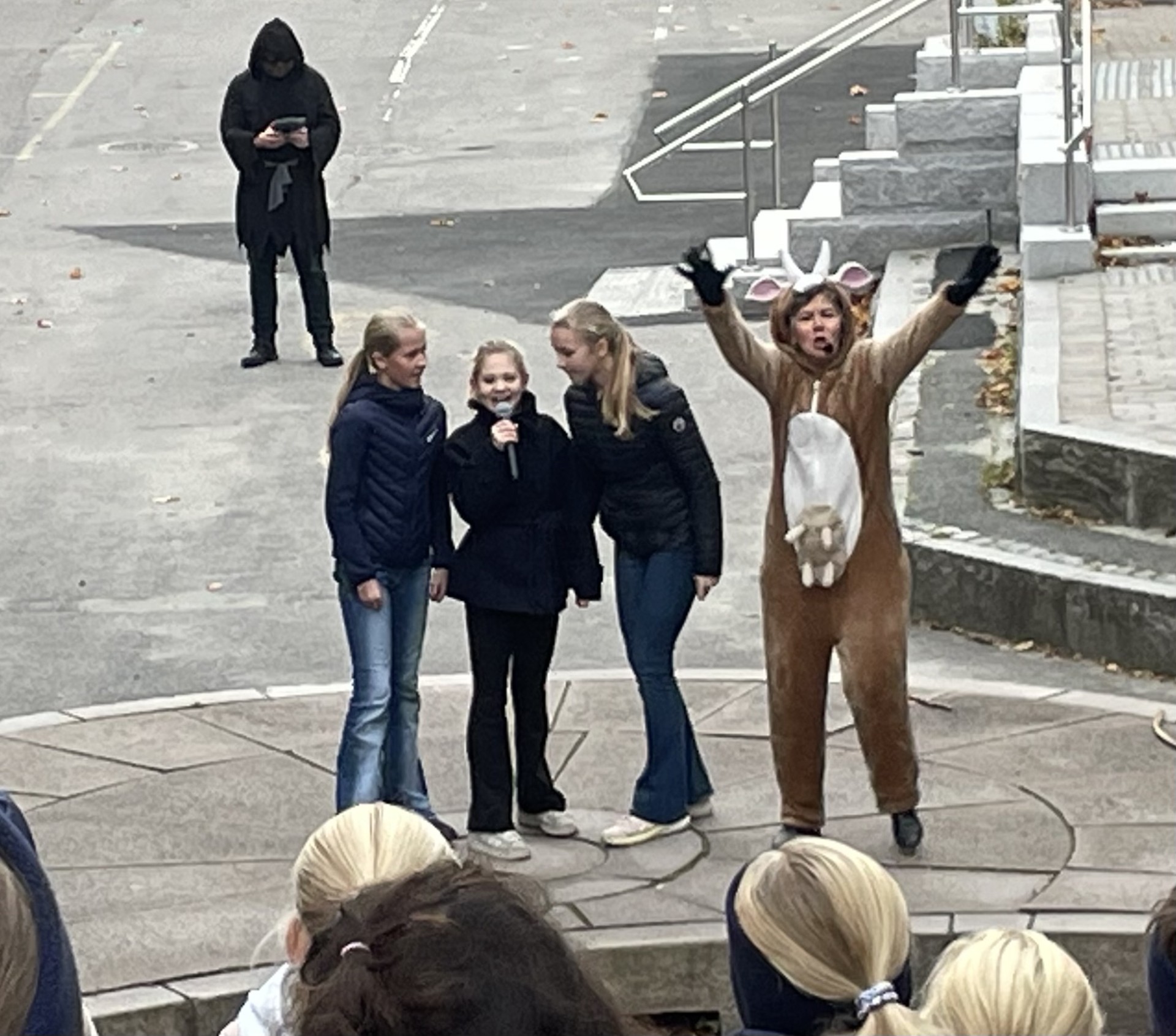 En gruppe mennesker som står på en gate med en person i hestemaske